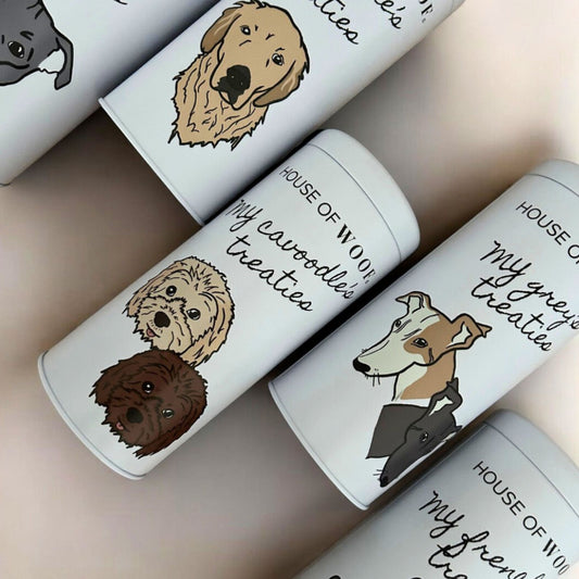 White dog treat tins with illustrations of dogs and text on a beige background