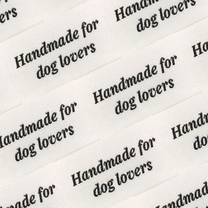 Close-up of white fabric labels with black text reading “Handmade for dog lovers,” used for House of Woof handmade pet accessories.